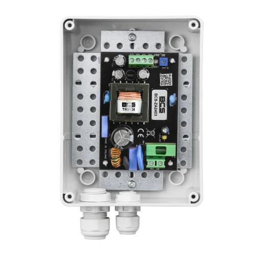 Zasilacz BCS-ZA2403-S o napięciu 24V i prądzie 3A, zamknięty w solidnej, prostokątnej obudowie z widocznymi elementami elektronicznymi i złączami. Obudowa posiada dwa przepusty kablowe na dolnej krawędzi.