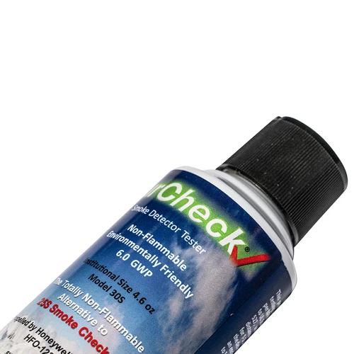 Na zdjęciu znajduje się puszka gazu testowego do czujek dymu z czarną nakrętką i kolorową etykietą zawierającą informacje o produkcie. Etykieta jest w języku angielskim i podkreśla, że produkt jest przyjazny dla środowiska i niepalny.