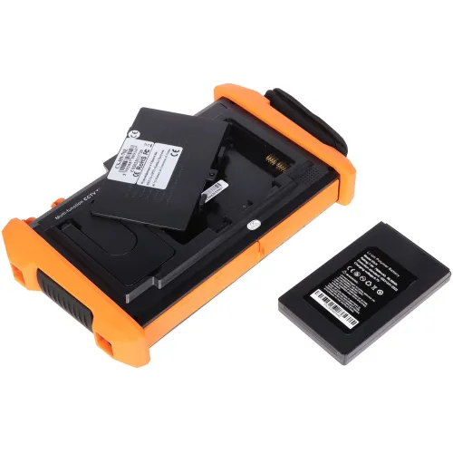 Na zdjęciu znajduje się pomarańczowo-czarny tester CCTV z otwartą komorą na akumulator, obok którego leży wyjęty akumulator. Urządzenie ma solidną obudowę z gumowymi narożnikami, co sugeruje jego wytrzymałość i przenośność.