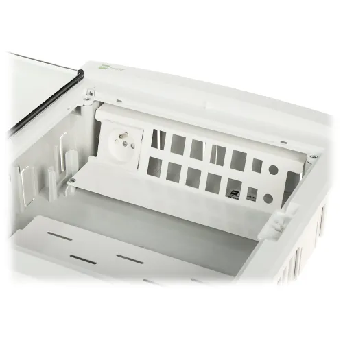 Zdjęcie przedstawia biały patch panel z gniazdem elektrycznym i miejscem na montaż modułów. Panel jest otwarty, ukazując wnętrze z miejscem na okablowanie.