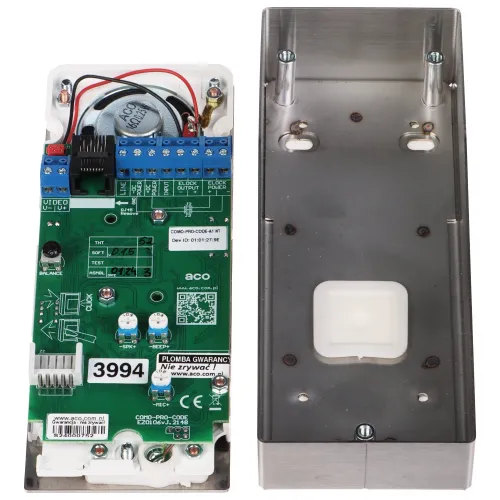 Zdjęcie przedstawia wnętrze obudowy elektronicznego urządzenia z widoczną płytką drukowaną i elementami montażowymi. Obok znajduje się metalowa pokrywa obudowy z otworami montażowymi.