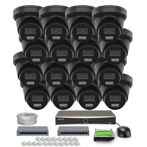 Na zdjęciu znajduje się zestaw do monitoringu składający się z szesnastu czarnych kamer, rejestratora, dwóch switchów, kabla, myszki oraz zestawu złączek. Kamery są ułożone w czterech rzędach, a pozostałe elementy zestawu są rozmieszczone poniżej.