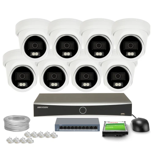 Na zdjęciu znajduje się zestaw do monitoringu składający się z ośmiu kamer, rejestratora, kabla, myszki, przełącznika sieciowego oraz karty pamięci. Wszystkie elementy są ułożone na białym tle, a kamery są rozmieszczone w dwóch rzędach.